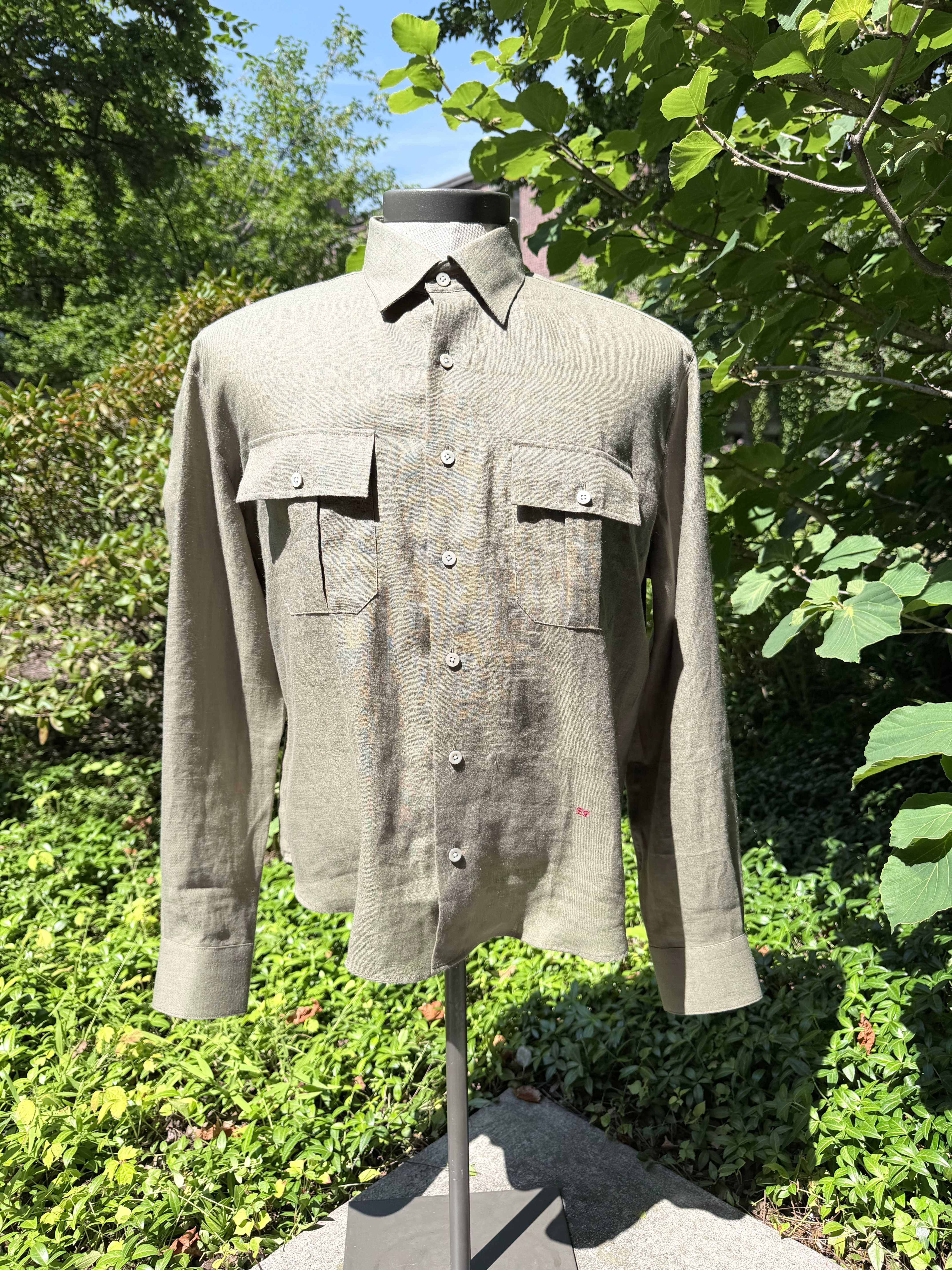 Olive linen long-sleeve shirt with two flap chest pockets on a form